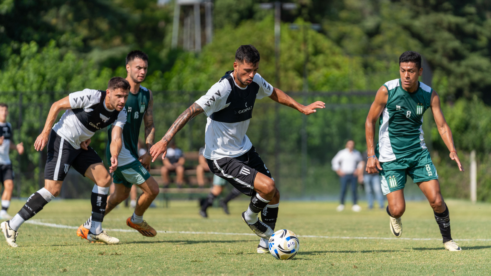 Footballers dribbling and competing on the pitch